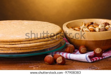 cakes for cake on glass stand and nuts on wooden table on brown background