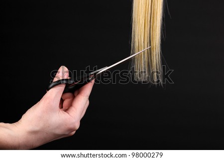 Shiny blond hair in hairdresser\'s hands isolated on black