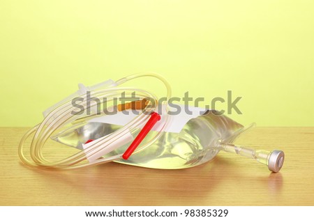 Bag of intravenous antibiotics and plastic infusion set on wooden table on green background