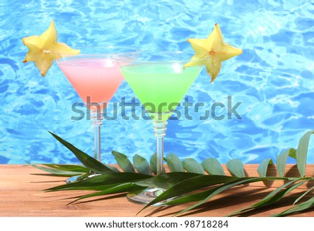 Glasses of cocktails on wooden table on blue sea background