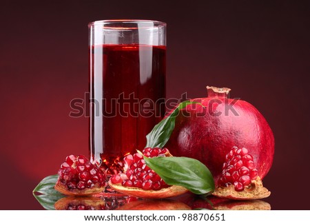 ripe pomergranate and glass of juice on red background