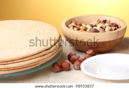 cakes for cake on glass stand and nuts on table on yellow background