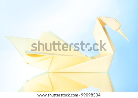 Origami paper swan on blue background