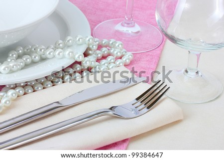 Table setting with fork, knife, plates, beads and napkin