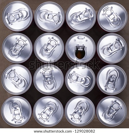 16 drink cans with one opened. Top view.