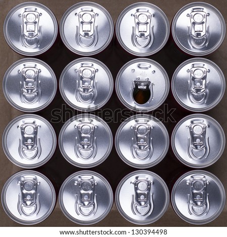 16 drink cans with one opened. Top view.