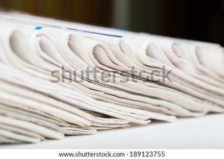 Assortment of folded newspapers closeup. Shallow DOF. Breaking news, journalism, power of the media, newspaper and magazine ads and subscription concept. Great as a web page banner or header and more.