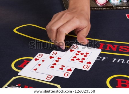 Hand dealer deals the cards of Hearts suit eight, nine, ten to play poker on the table in a casino.