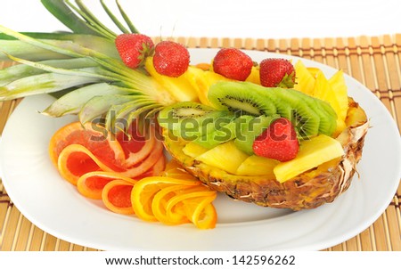 Fresh fruit beautifully sliced ??on  plate: pineapple, grapefruit, oranges, strawberries, kiwi.