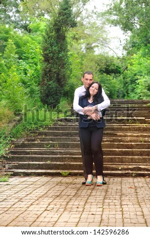 Young man and woman are embracing in the park on   background of the old staircase.
