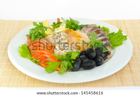 Dish with sliced ??salmon, herring, sturgeon, decorated with green olives lemon.