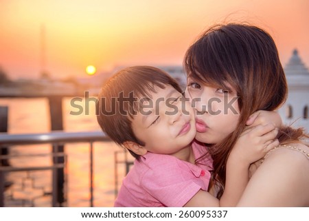 son smiling and mom kissed, thai family