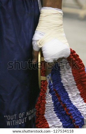 Cropped view image of the hand of a black American boxing champion wearing a handwrap and holding a medal with a red, white and blue ribbon