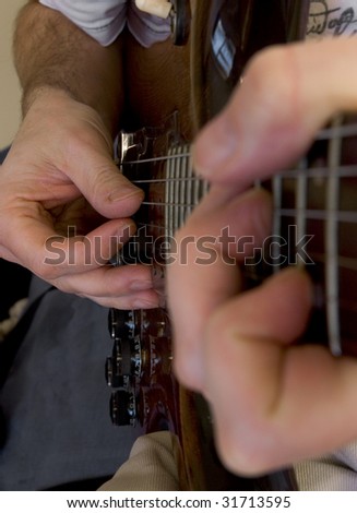 A close up of an electric guitar being played, showing both hands along the neck