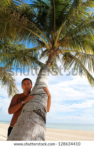 Man with tongue poking out under palm tree on beach