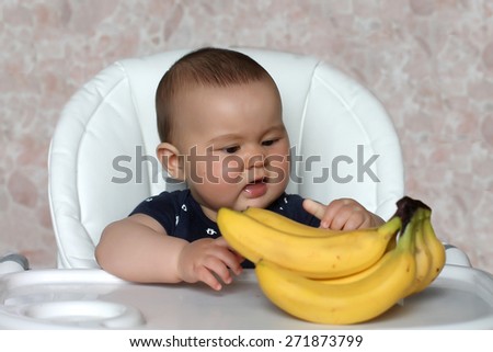 Baby with banana at chair