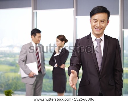 young confident asian business executive reaching out for a handshake.