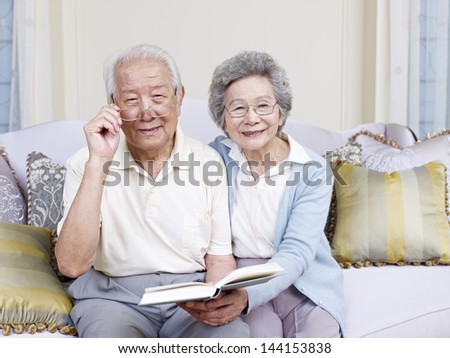 senior asian couple reading a book together at home.