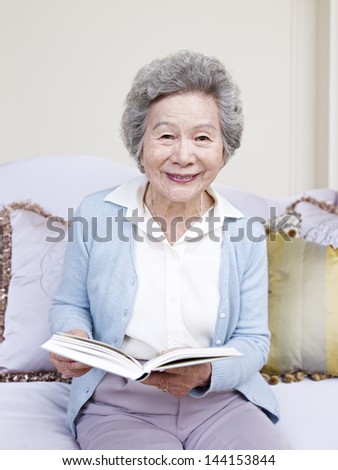 senior woman holding a book and smiling.