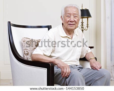 portrait of an asian senior man sitting in an armchair.