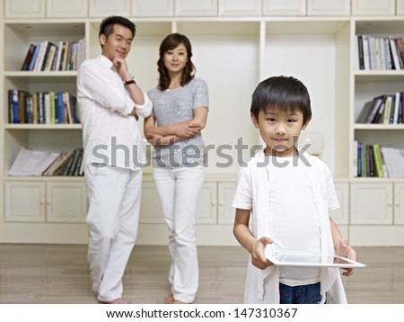 6-year old asian boy with proud parents in background.