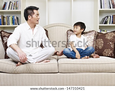 father and son having a conversation on couch at home.