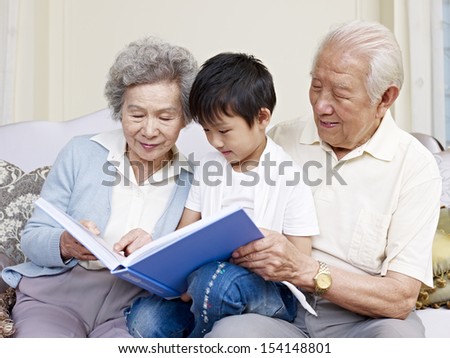 grandparents and grandson reading a book together.