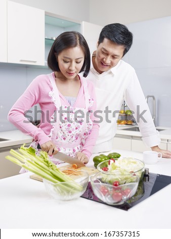 young asian couple preparing meal together in kitchen.
