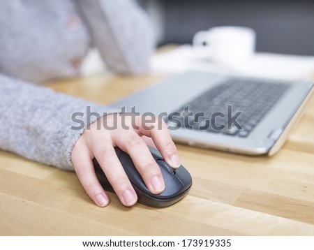 a female\'s hand clicking a mouse.