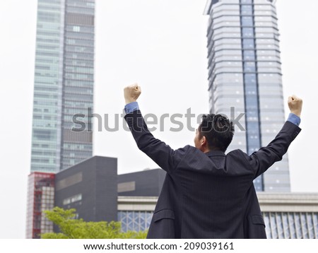 asian businessman celebrating with arms raised.