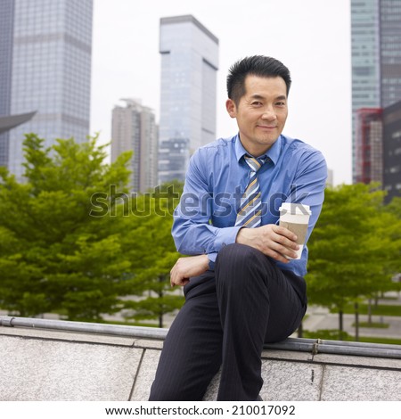asian business executive taking a break in city park.