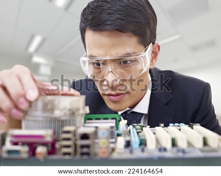 young asian man fixing computer with protective eyewear