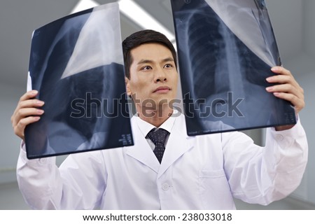 asian doctor looking at x-ray films.