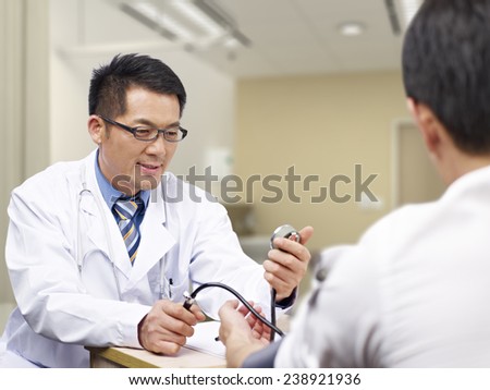 asian doctor measuring blood pressure of a patient.