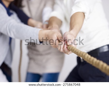 group of businesspeople playing tug-of-war, focus on hands.