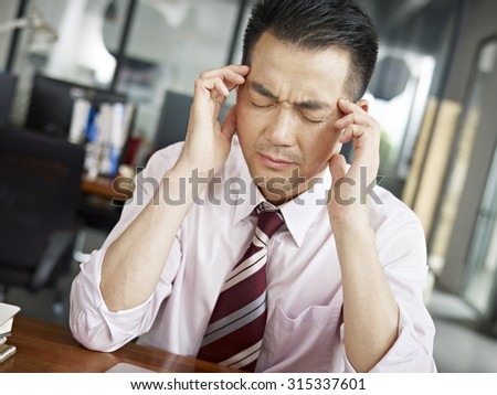 asian businessman having a headache in office.