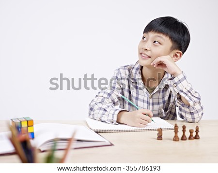 10 year-old asian elementary schoolboy looking away while studying.