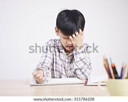 10 year-old asian elementary schoolboy appears to be frustrated while doing homework.