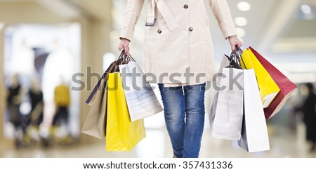 woman with colorful shopping bags walking in modern mall.