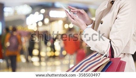 hands of a young woman using mobile phone in modern shopping mall.