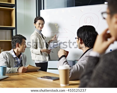 young asian business executive facilitating a discussion or brainstorm session in meeting room.
