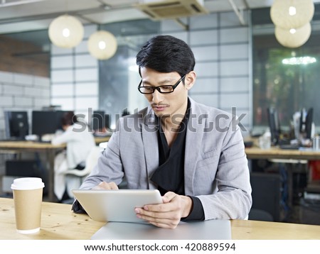 young asian business man working in office using tablet computer.