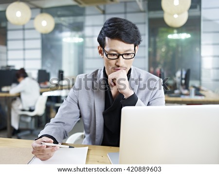 young asian business man working in office using laptop computer.