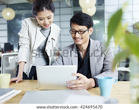 young asian business people sitting at desk working together using laptop computer.