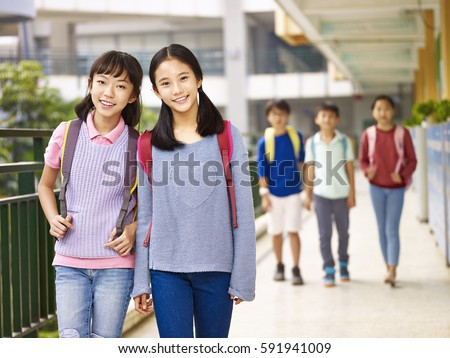asian elementary school girls walking in classroom building.