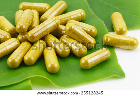 Turmeric Powder in Transparency Hard Gelatin Capsules with Green Natural Leaves on White Background.