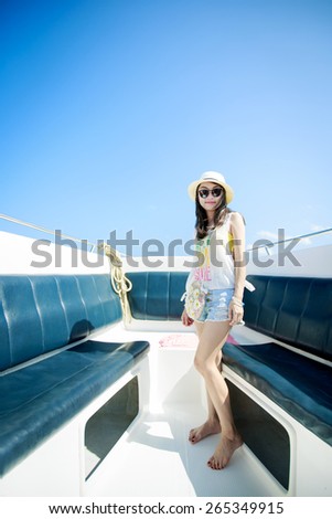 Young woman posing on a power speed boat with hat and sunglasses