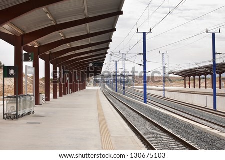 Railway station platforms with trolleys clock information signals and electricity transmission system to railroad. Nobody