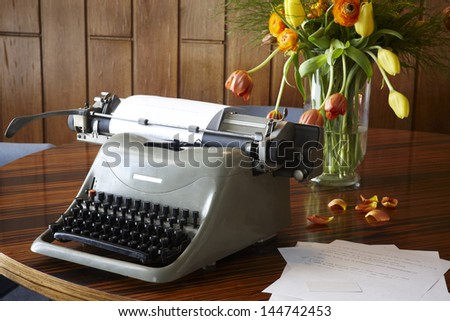 Old typewriter on table still life with flowers and wood background