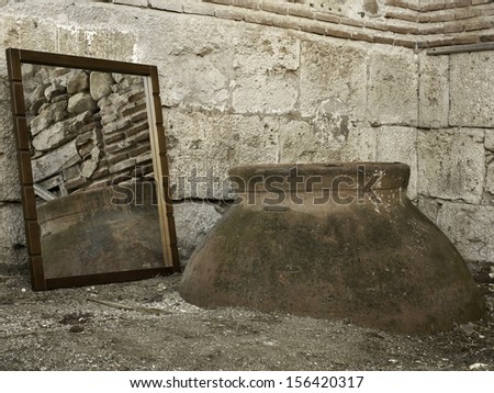 Stone Wall and old wine container reflected on a mirror black and white vertical